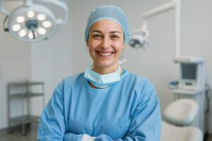Image of a smiling, confident surgical dentist in a sterile operating room. No text on the image.